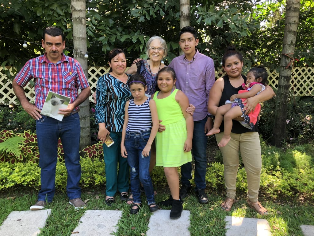 Lori poses in real life with 7 members of her sponsor child's family